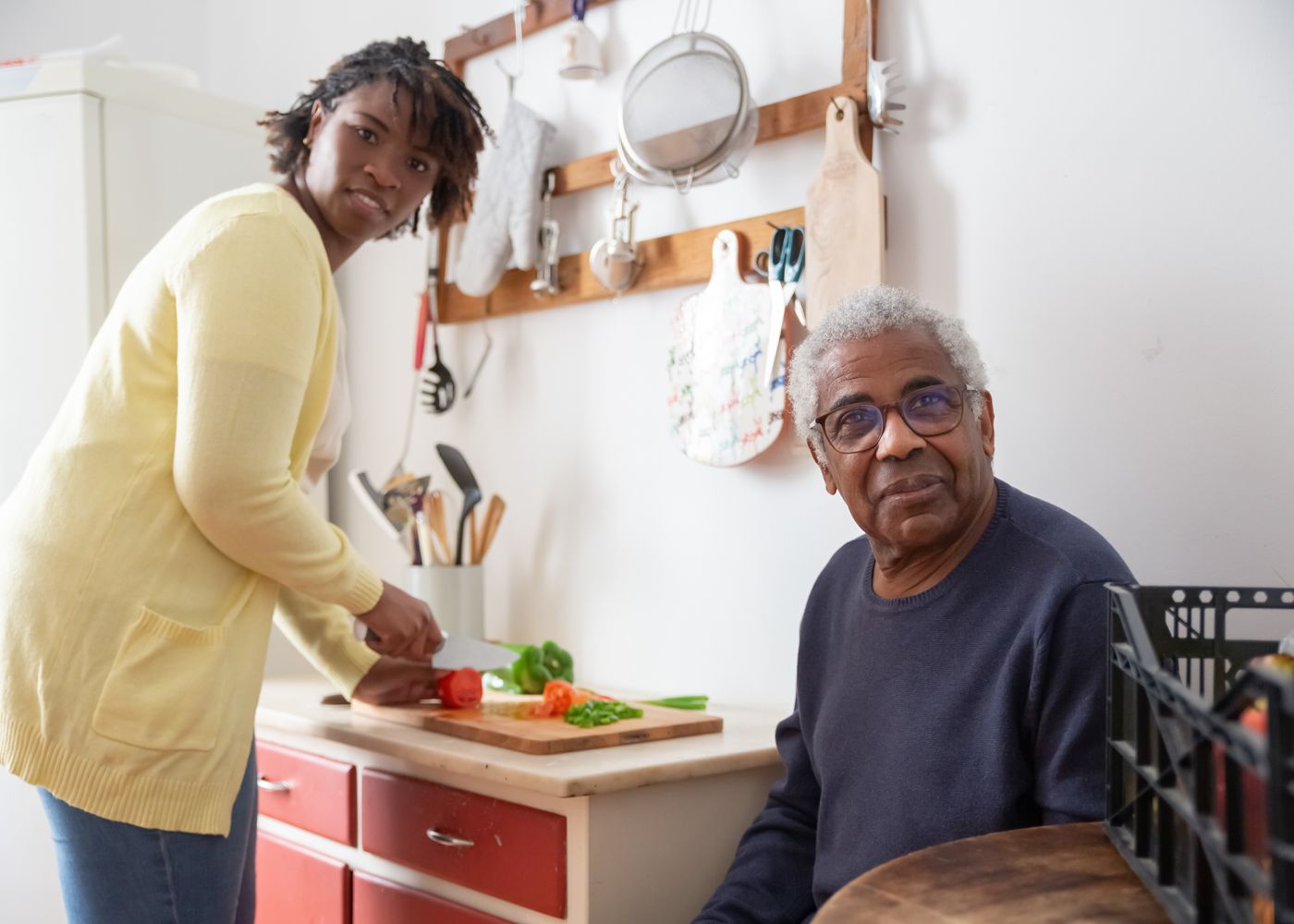 Older man spending time with another adult during meal preparation at home