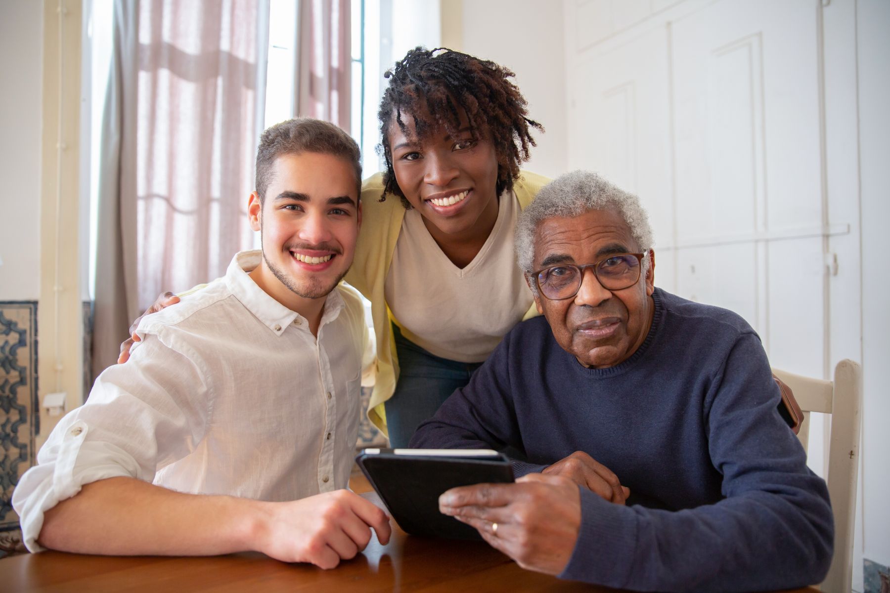 Older man spending time at home with two companions around a tablet
